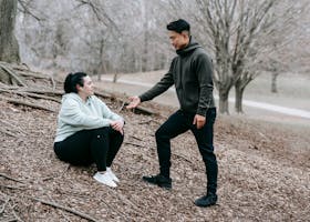 Man and woman engaging in fitness training in a natural park environment.