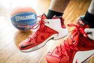 Close-up of red basketball sneakers in action with a Spalding ball on wooden floor.